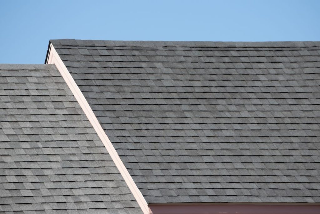Roof shingles on top of the house against blue sky with cloud, dark asphalt tiles on the roof background. North Oaks, Minnesota