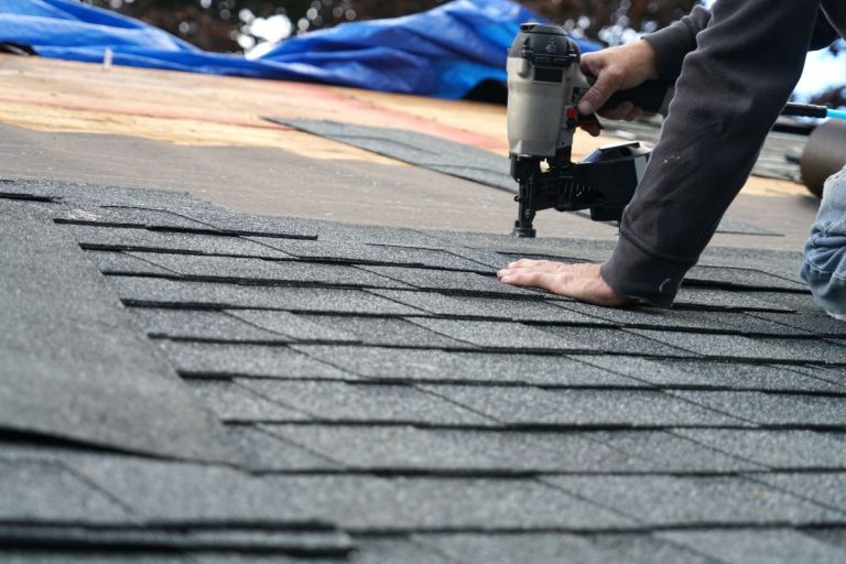handyman using nail gun to install shingle to repair roof, North Oaks